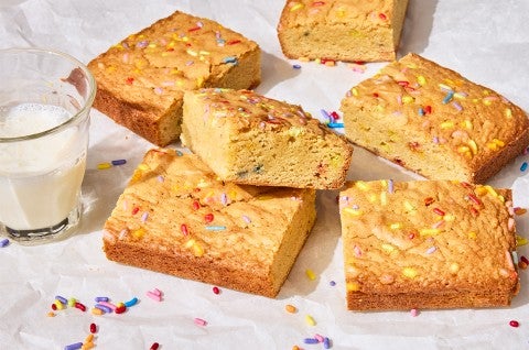 Small-Batch Birthday Cake Blondies on a counter with a glass of milk - select to zoom