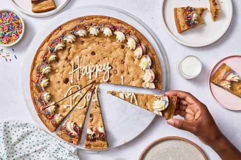 Removing a slice of chocolate chip cookie cake seen from above. - select to zoom