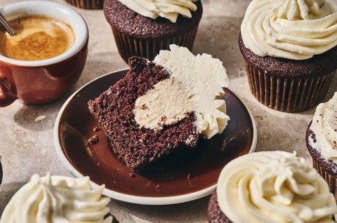 Irish Cream Cupcake on a plate with other cupcakes and a cup of coffee in the photo. - select to zoom