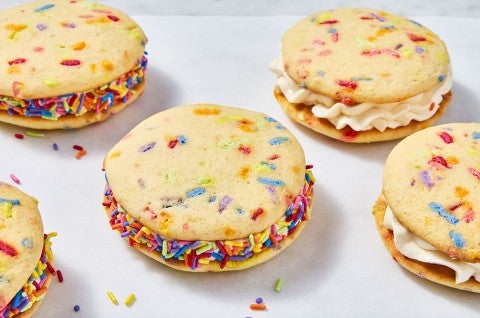 Confetti Whoopie Pies on a counter with sprinkles decorating the filling around the edges. - select to zoom
