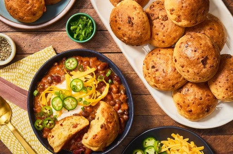 Gluten-Free Bacon Cheddar Rolls on a platter with a bowl of chili next to it. Seen from above. - select to zoom
