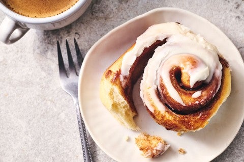 A Sourdough Cinnamon Roll on a plate accompanied by coffee - seen from above. - select to zoom