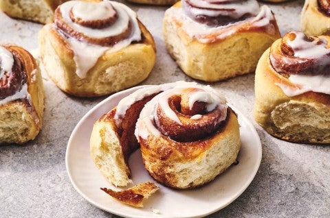 A Sourdough Cinnamon Roll on a plate accompanied by coffee. - select to zoom