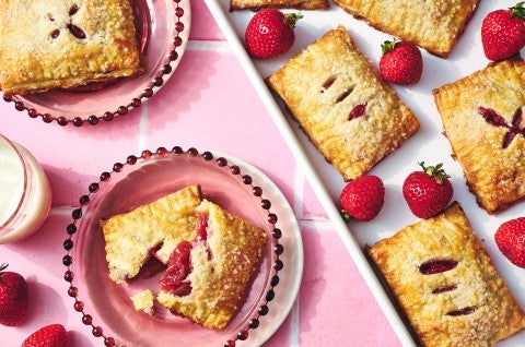 Strawberry Hand Pies on plates with one broken to show the strawberry filling - select to zoom