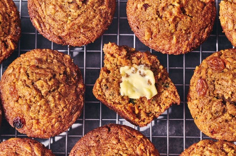 Morning Glory Muffins on a cooling rack. One is split with butter on it. - select to zoom