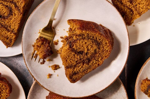 A slice of Pumpkin Espresso Bundt Cake on a plate with a bite on a fork - select to zoom