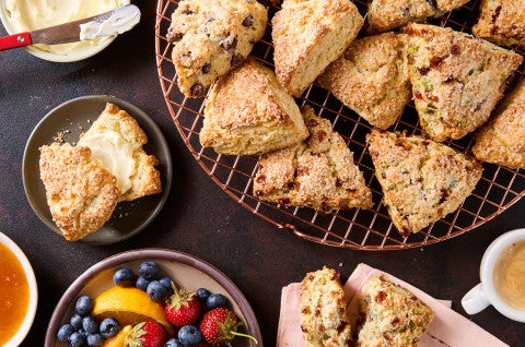 Scones on a cooling rack and plates with fresh fruit - select to zoom