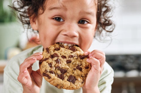 A child eating an oatmeal chocolate chip cookie - select to zoom