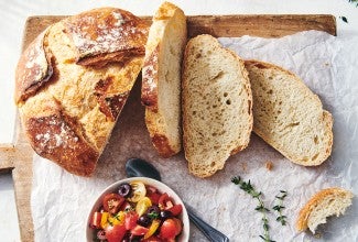 A loaf of crusty bread that has a few slices cut off, showing off the thin and crisp crust and even interior structure.