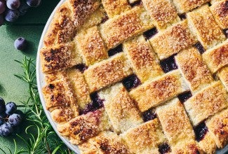 Concord Grape Pie photographed from above showing a lovely woven pie crust on top with brown hues and coarse sugar.