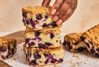 A stack of Emancipation Breakfast Cake slices with a hand placing the top slice