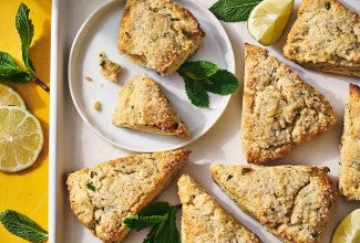 Mojito Scones on a plate and a platter with limes and mint leaves decorating the photo.