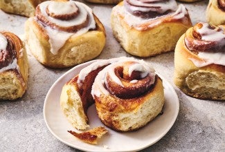 A Sourdough Cinnamon Roll on a plate accompanied by coffee.