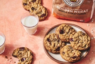 Whole Wheat Oatmeal Cookies on a plate with a glass of milk and a cookie with a bite taken out on a counter seen from above
