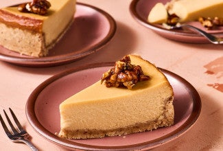 A slice of Maple Pecan Cheesecake on a pink plate, seen from the side