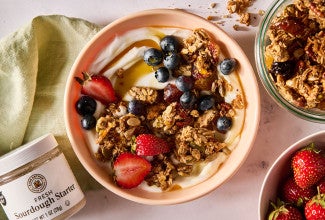 Sourdough Granola atop some yogurt in a bowl along with fresh fruit