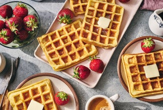 Waffles arranged on plates with fresh fruit