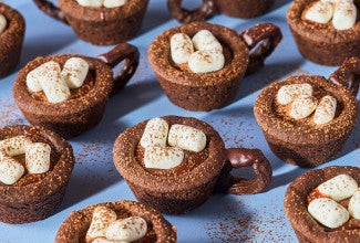Hot Cocoa Cookie Cups arranged on a blue countertop.
