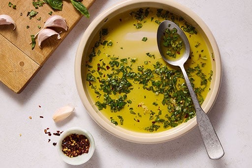 Oil in a bowl with herbs and seasoning.