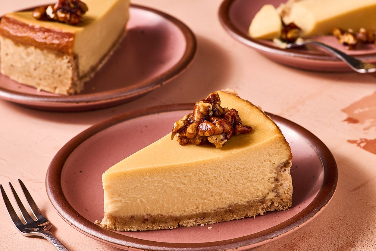 A slice of Maple Pecan Cheesecake on a pink plate, seen from the side
