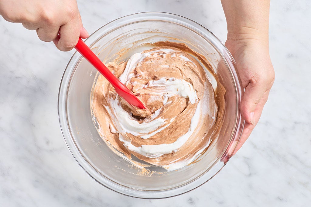 Mixing the filling for No-Bake Chocolate Cheesecake Bars in a glass bowl with a rubber spatula