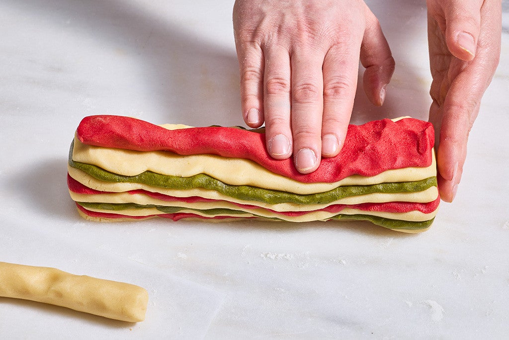 Pressing a stack of colored Ribboned Peppermint Shortbread Cookies dough