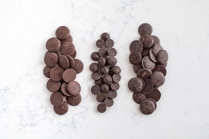 Three small piles of chocolate including chocolate chip, candy melts, and coveture chocolate