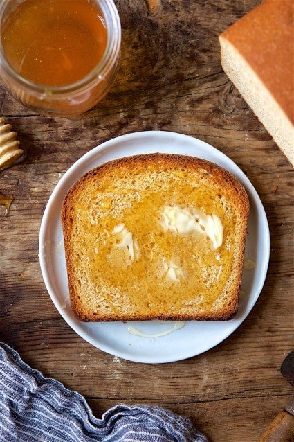 Slice of 100% whole wheat sandwich bread, toasted and buttered, on a plate.