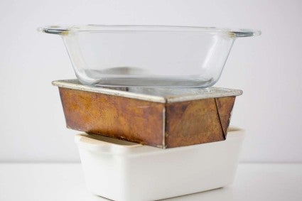 A glass pan, metal pan, and ceramic pan stacked on top of each other