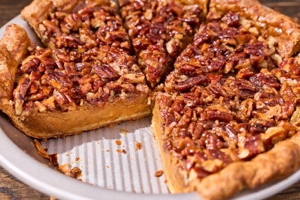 Photograph of pumpkin pecan pie in a pie tin with a slice missing.