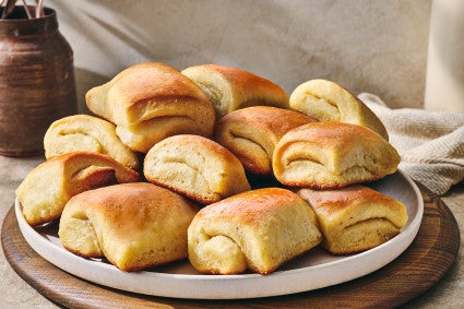 Parker house rolls stacked on a plate showing a buttery gloss and perfect folded bake.