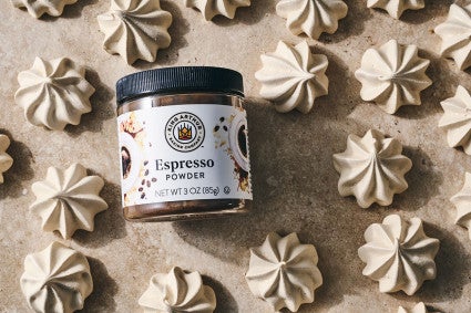 Espresso Meringue powder from King Arthur Baking in laid on its side among many meringues spread on a neutral textured counter.