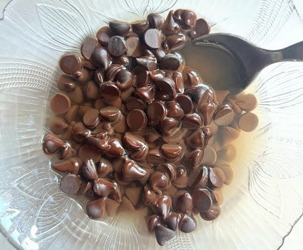 A bowl of chocolate chips and heated water ready to be stirred into a smooth water ganache.