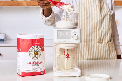 Adding flour to the top of the automatic sourdough feeder, the Sourdough Sidekick