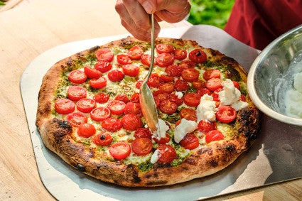 Adding fresh mozzarella to caprese style NY pizza fresh out of the oven