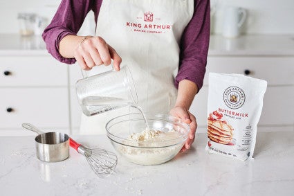 Baker pouring water to mix buttermilk pancake mix batter
