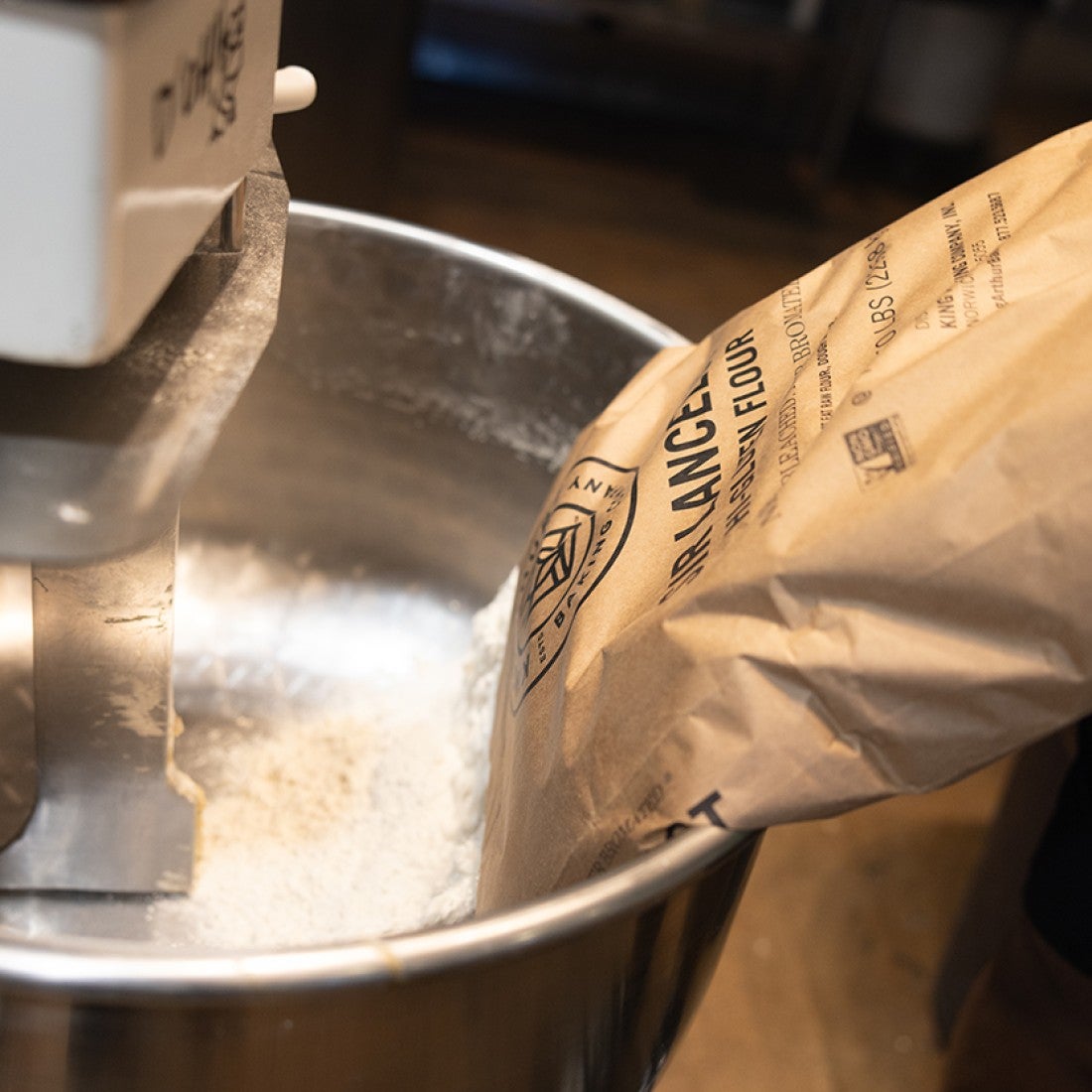Flour being poured into a stand mixer bowl in preparation of making dough. - select to zoom