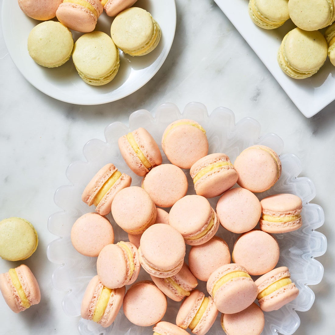 Macaron With Natural Colors arranged on plates atop a marble counter