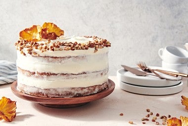 A Hummingbird Cake with a pineapple cream cheese frosting and dried pineapple and toasted nuts on top.