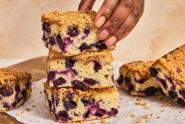 A stack of Emancipation Breakfast Cake slices with a hand placing the top slice