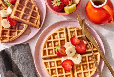 A Belgian Style Yeast Waffle on a plate with fresh strawberries and banana.