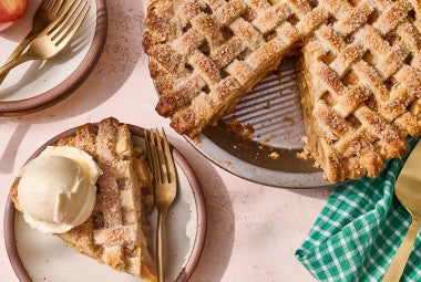 Gingered Apple Cream Pie seen from above with a lattice top crust and a slice on a plate topped with vanilla ice cream.
