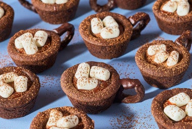 Hot Cocoa Cookie Cups arranged on a blue countertop.