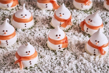 Snowman Meringues arranged on a counter with sugar snow